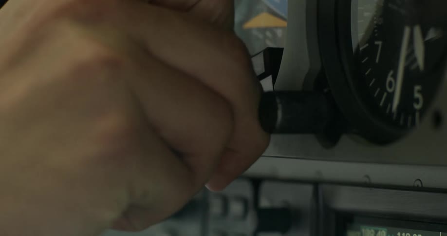 A man is adjusting on instrument on a cockpit panel