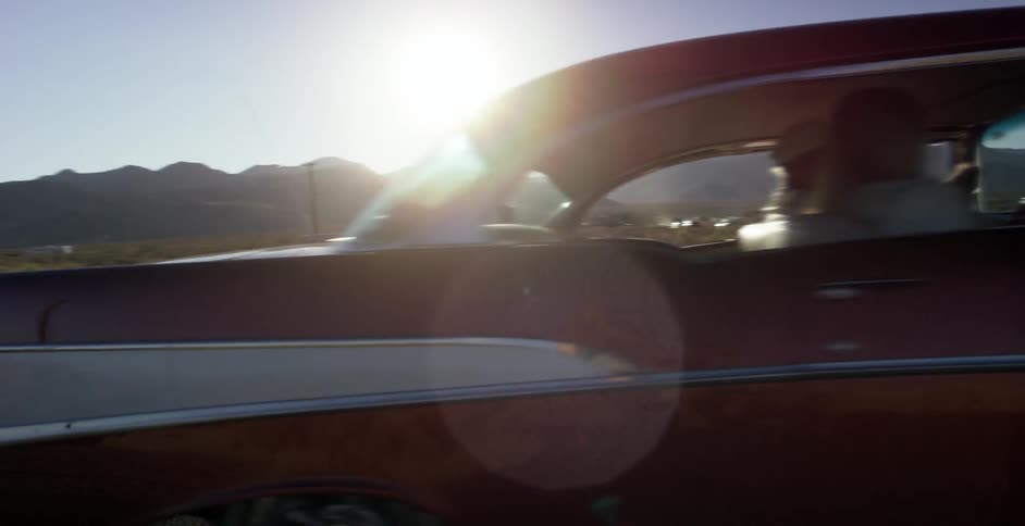 A red car drives off down the road