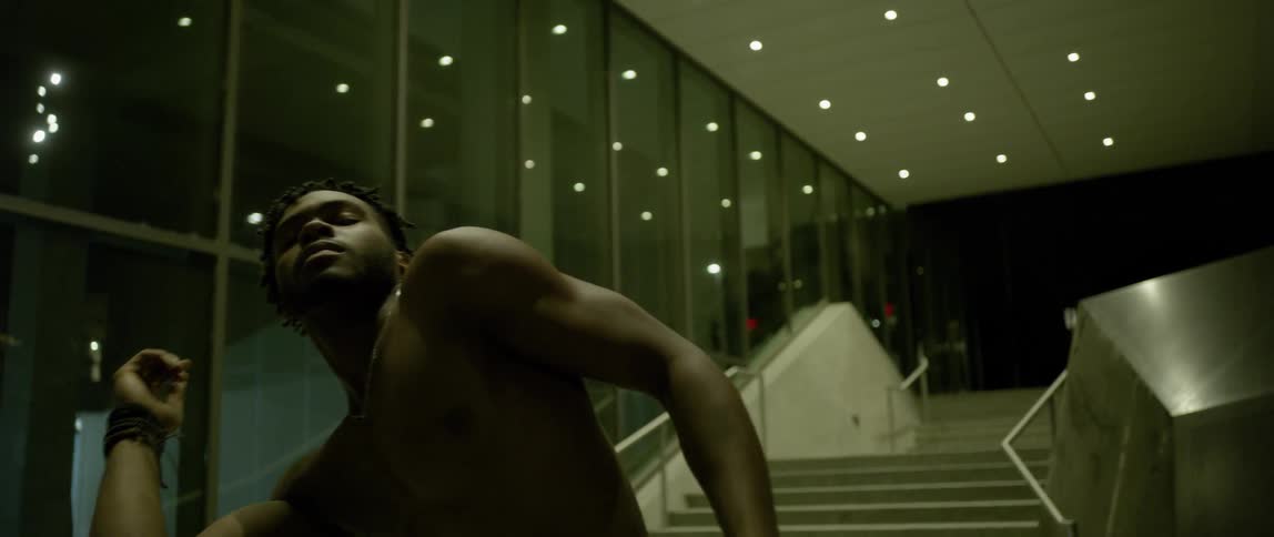 Shirtless man dances in city at night