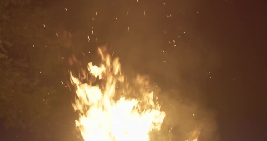 A fire sends smoke and sparks up into the sky at night