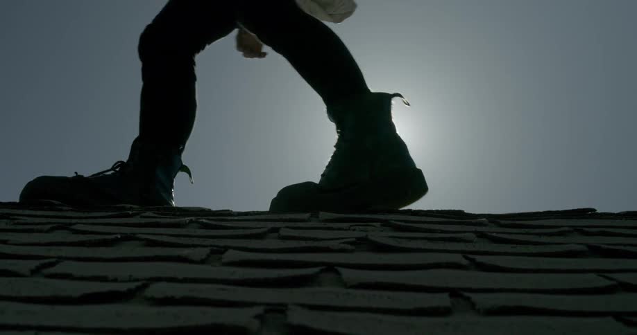 The sun shines on a man walking on a roof