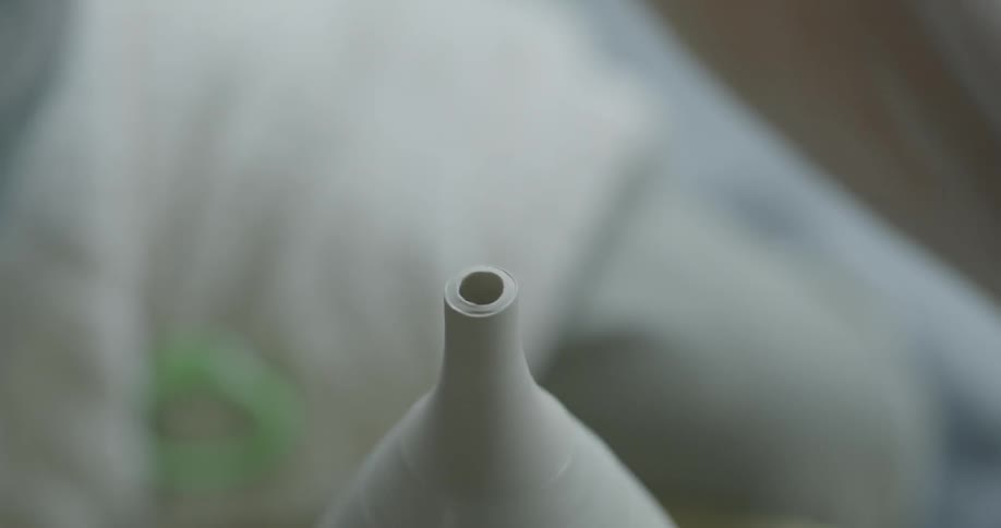 An artisan is working on a vase on a pottery wheel during the day