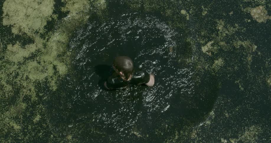 Man swims in mossy lake