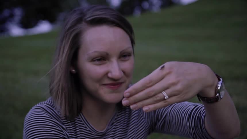A woman lets a firefly land on her hand
