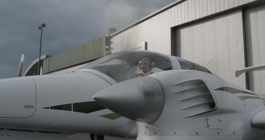 A man is sitting inside a small plane and starting it