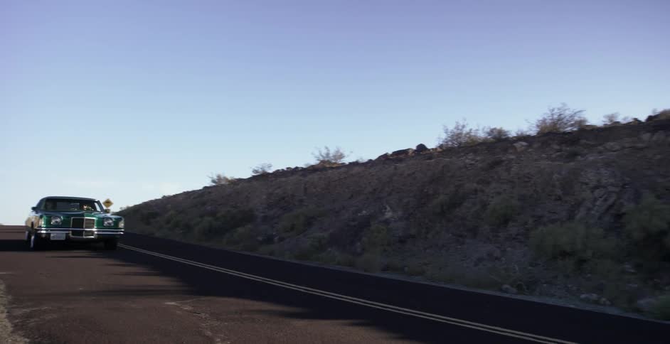 A car travels down a mountain road and around a curve