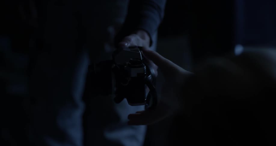 A man is handing someone a camera at night