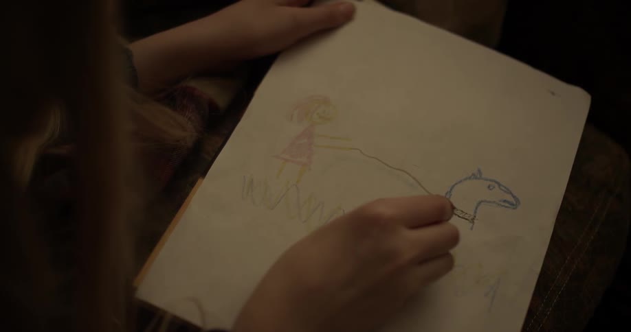 A girl draws with crayons