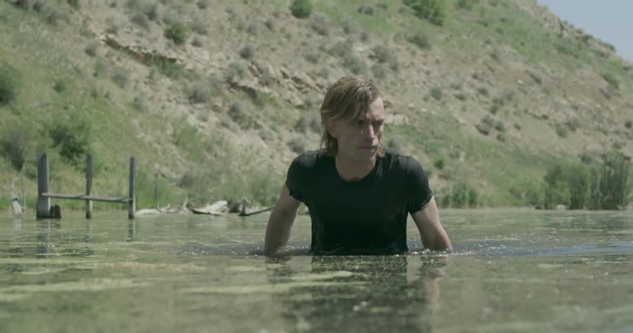 A man is walking through chest high deep water