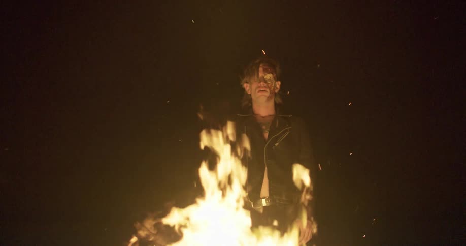 A man stands behind a fire
