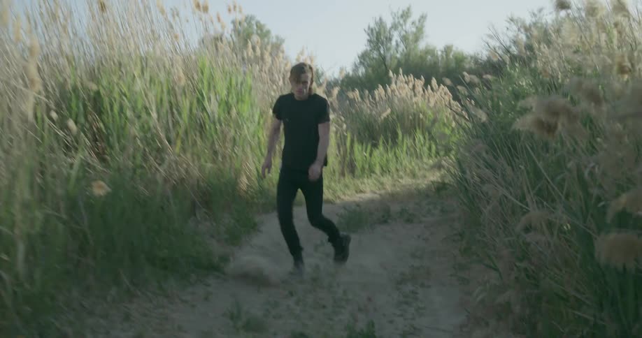 A man in black walks down a sandy path