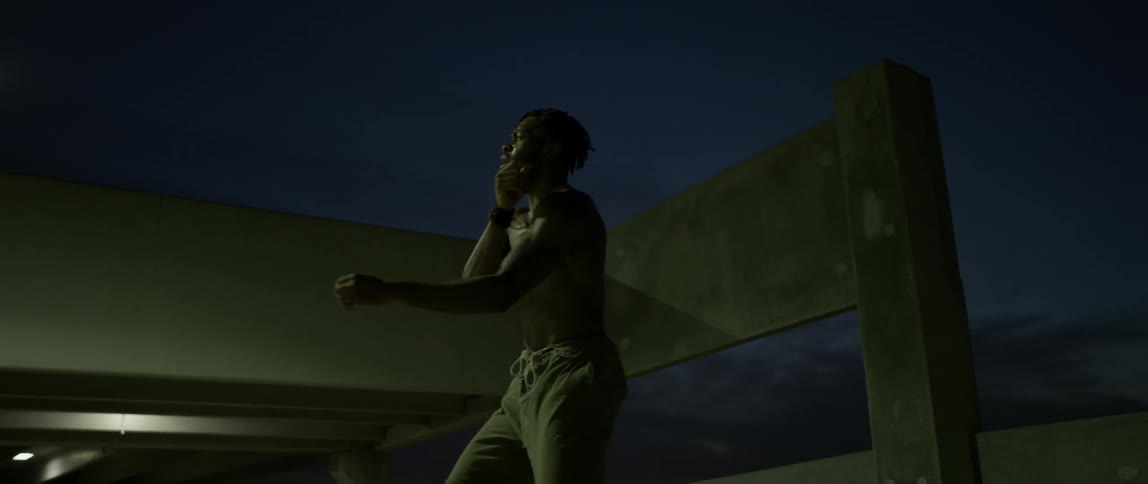 A man is dancing around at night near a parking garage
