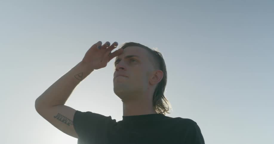 Man looks around while standing outside on a sunny day