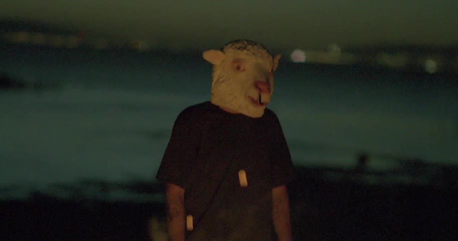 Man wears a sheep mask next to a bonfire