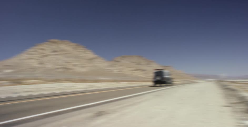 A jeep is driving down a desert highway