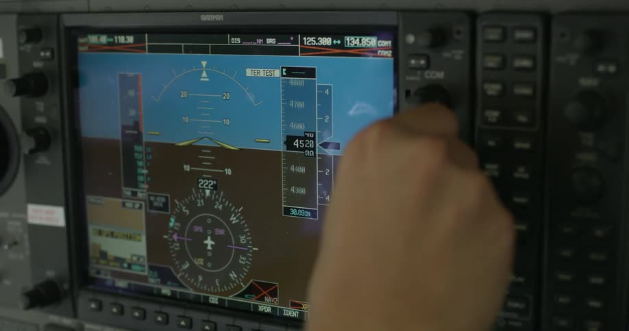 A pilot adjusts knobs in the cockpit