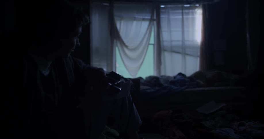 Man folds up note in dark bedroom
