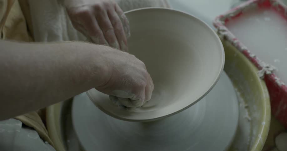 Someone is smoothing out a clay pot