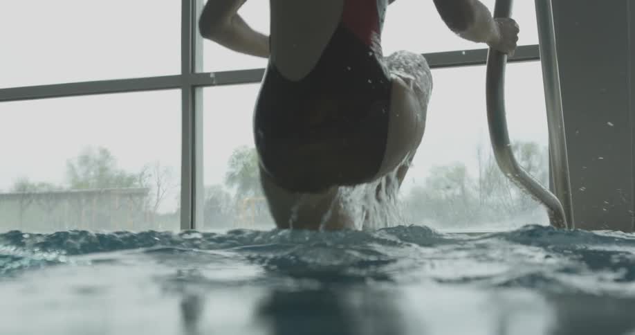A woman gets out of the water climbing up the ladder