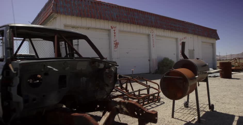 A chopped truck sits outside of a garage