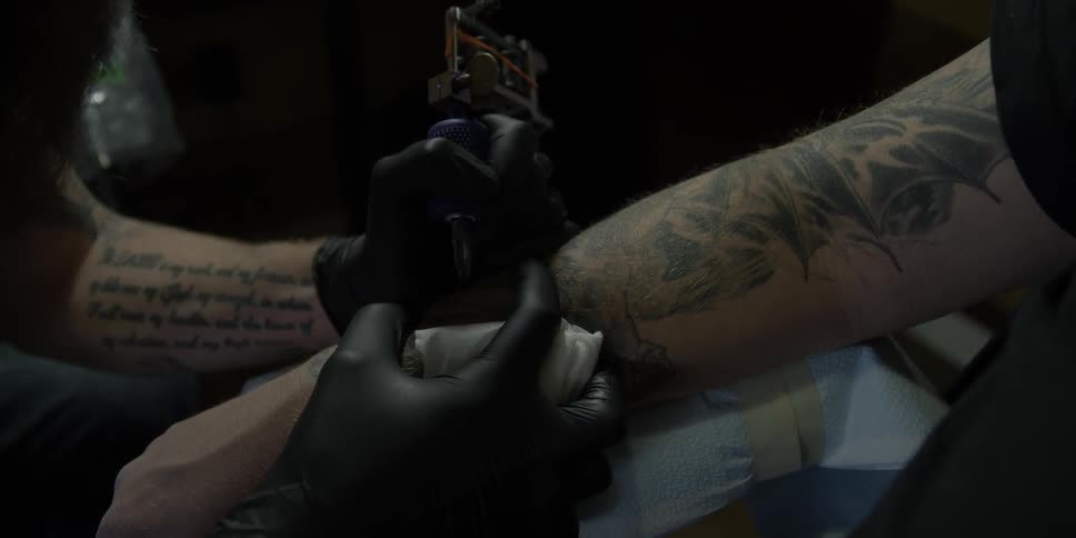 A man is giving a customer a tattoo