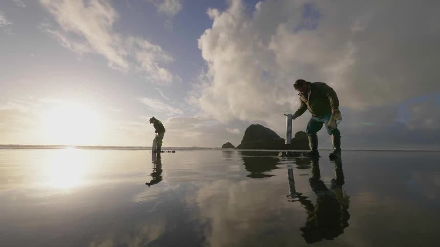 People working on a beach at a cloudy sunset
