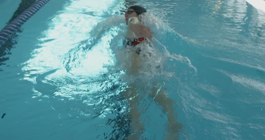 A woman is swimming in the blue water of the pool