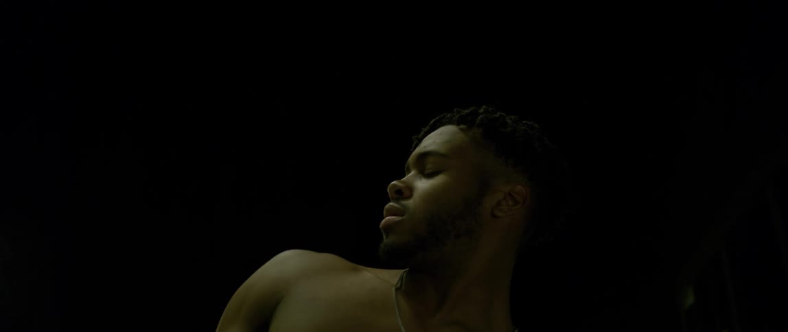 A shirtless man dances under an awning
