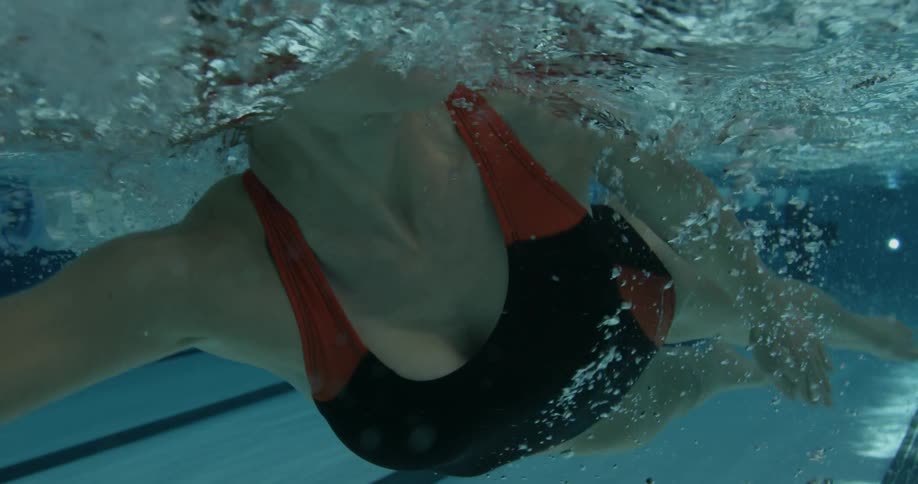 A woman is swimming underwater in a pool
