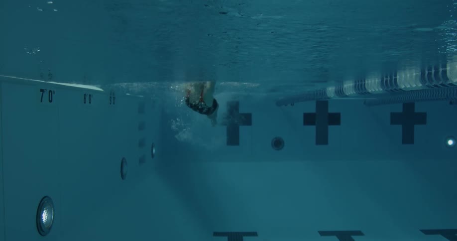 A woman is swimming forward in the water in the pool