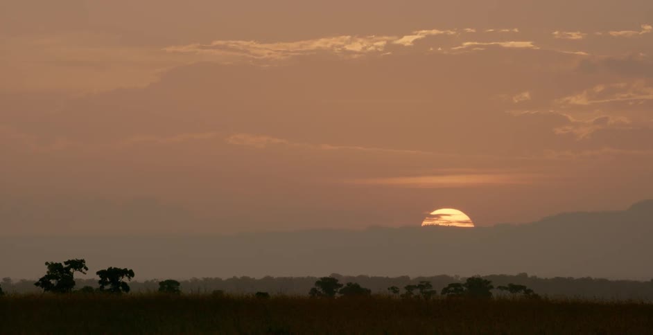 The sun is almost set behind the mountains in the distance