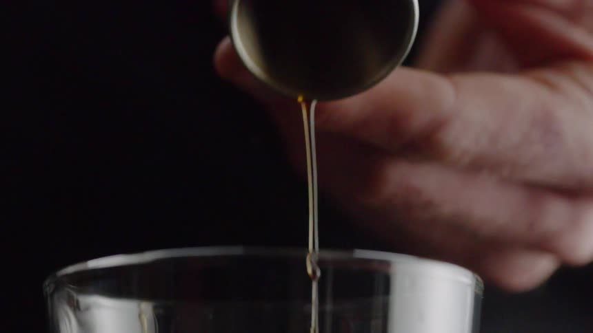 A man is pouring a brown liquid into a glass