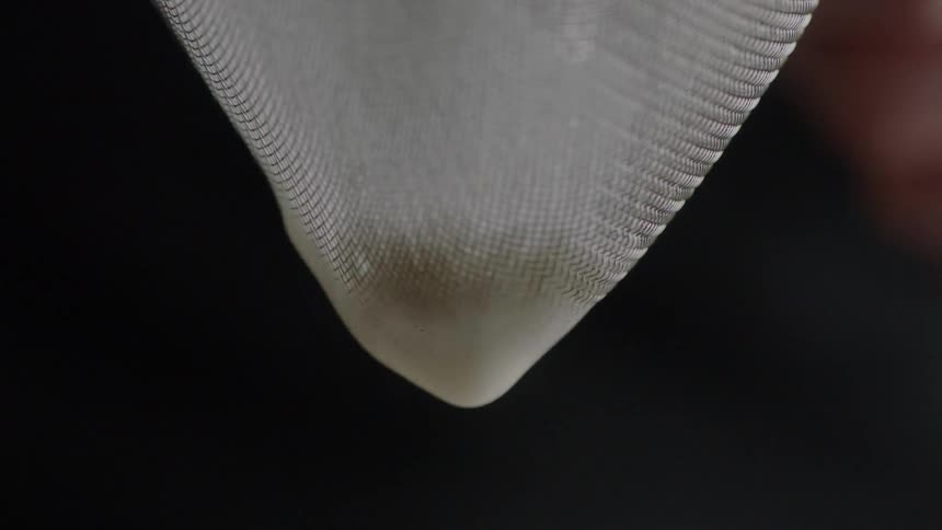 White liquid drips through white mesh