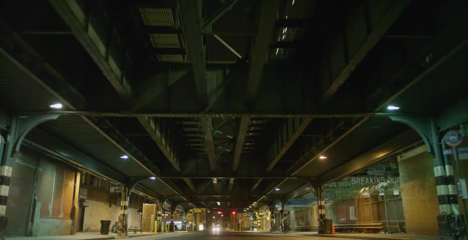 A car is traveling under the subway overpass