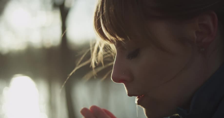 Woman claps and blows' hands to keep warm on a chilly day