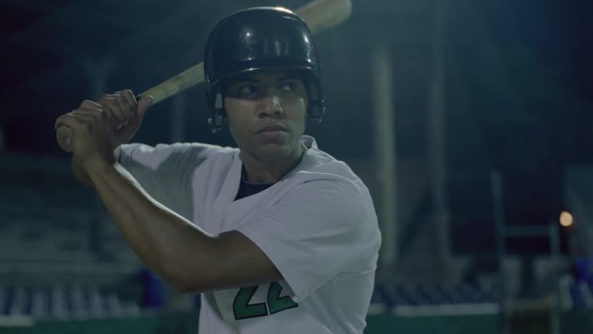 A baseball player swings at a pitch thrown at him