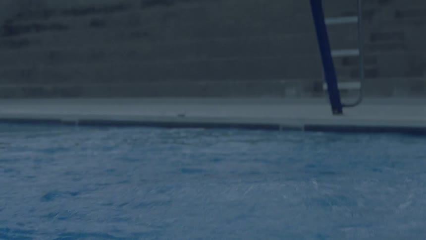 Someone dives into a large swimming pool and then surfaces