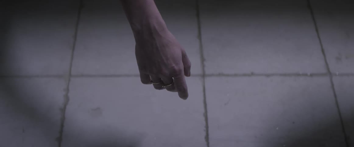 A woman's hand is dangling above a tile floor