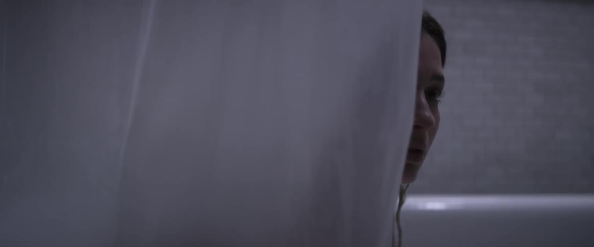 Woman peeks out from behind a curtain