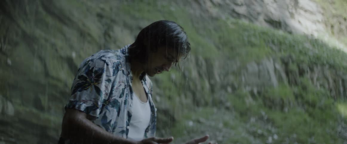 A man is soaking wet in the rain by a cavern