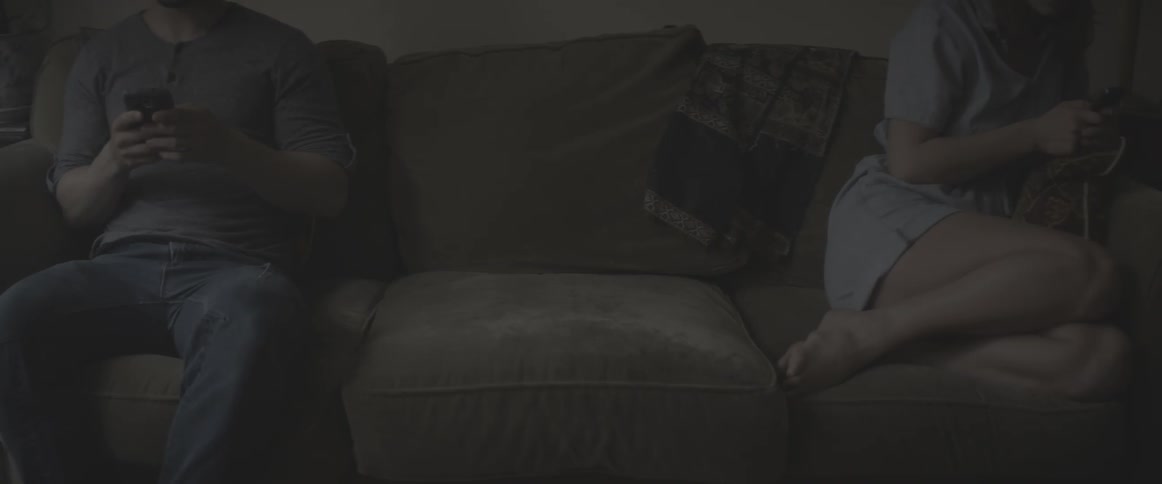 A man and woman are sitting on a couch ignoring each other