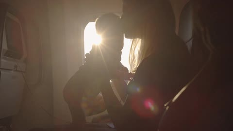 A woman is holding a baby on a plane