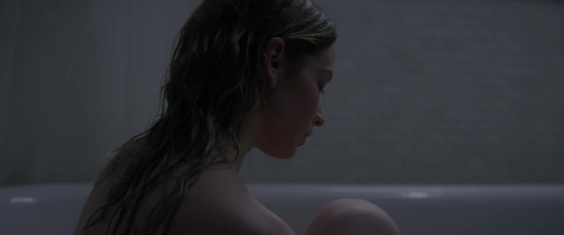 A woman is sitting in a bathtub with her knees to her chest