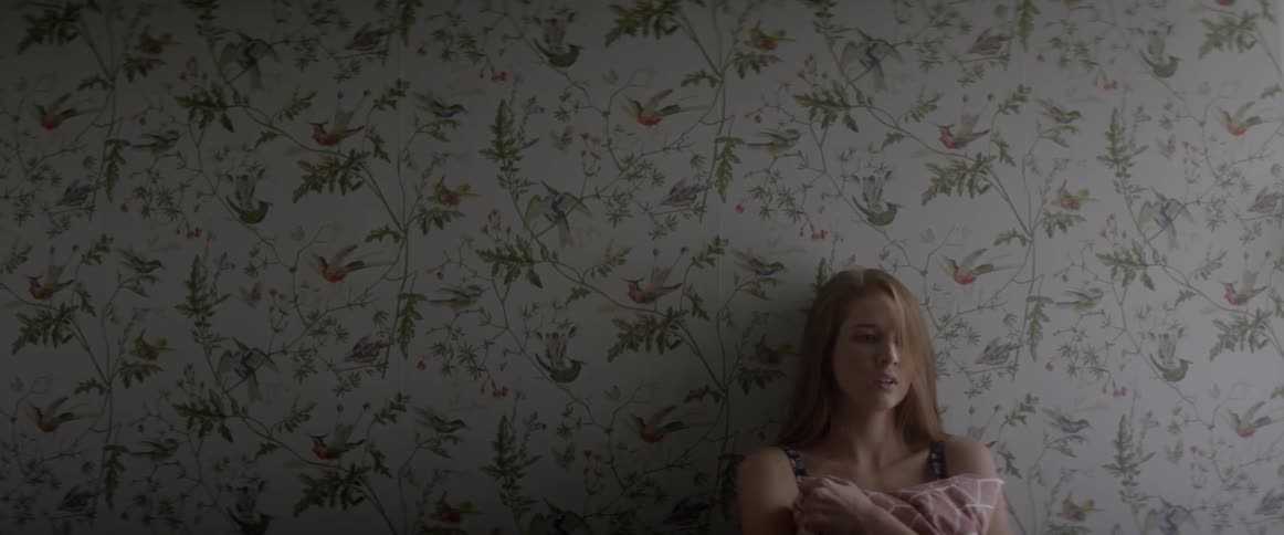 A woman looks sad against a wall
