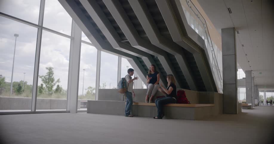 Three women in a building foyer have a conversation using sign language