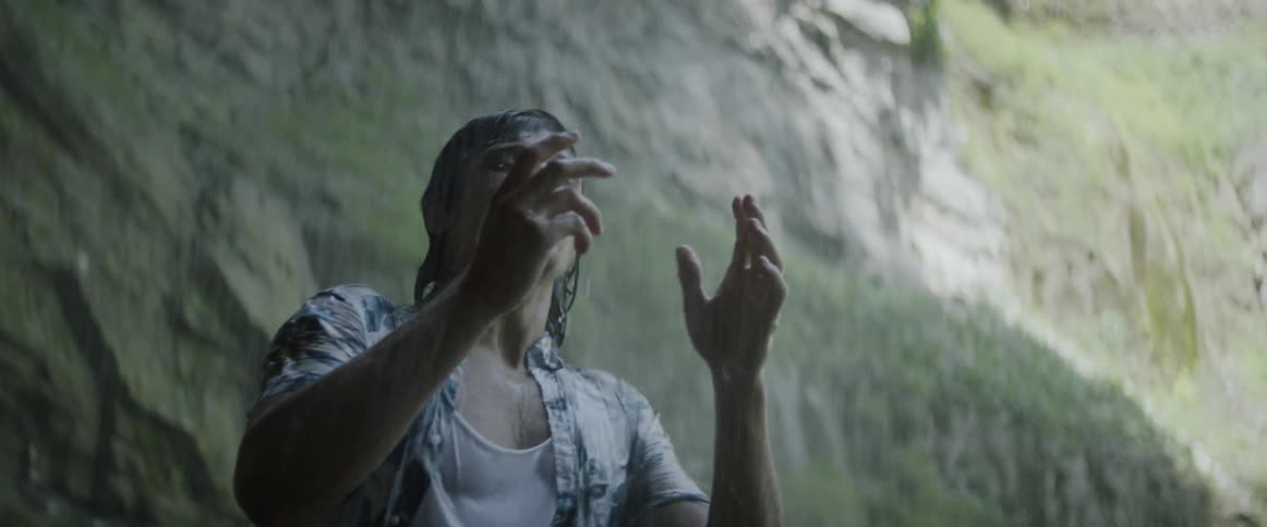A man is excited as cold water sprays all over him from above
