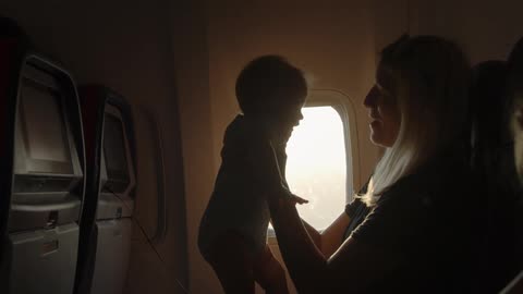 A woman is sitting on a plane with a baby