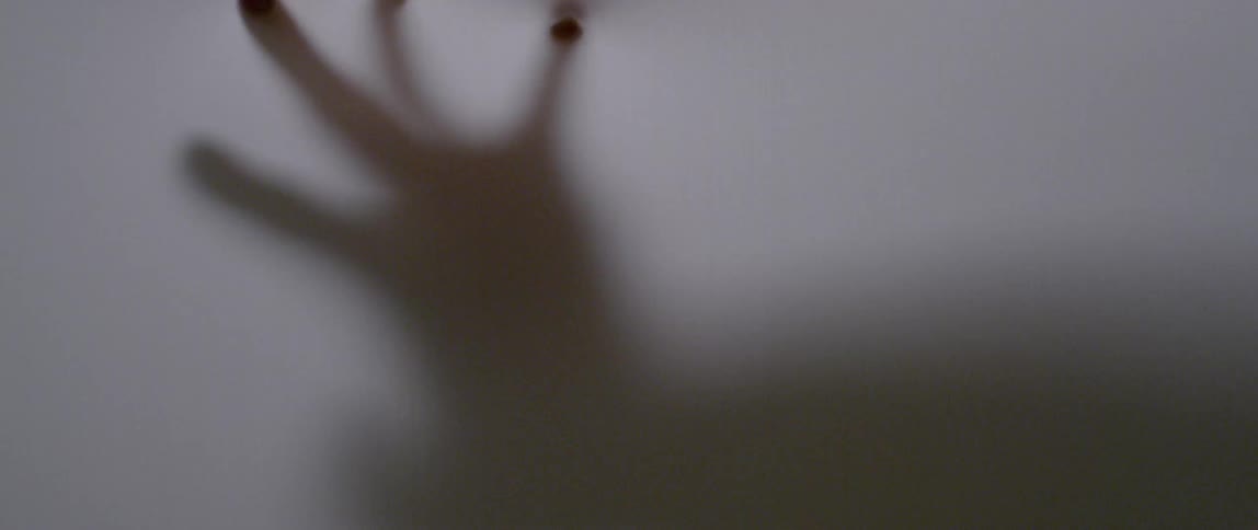Person's hand moves behind a white screen