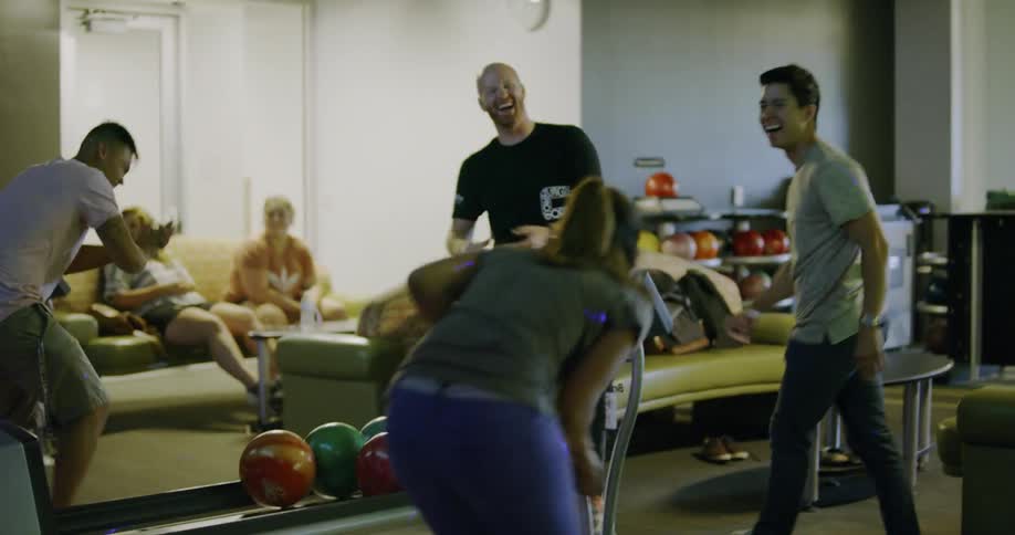 Friends laugh and clap as they bowl during the day