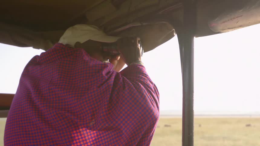 A man is using binoculars to look out over a field